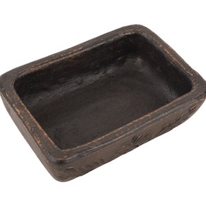 Pu&ograve; includere: Un piccolo piatto rettangolare in ceramica nera con un bordo leggermente rialzato. Il piatto ha una superficie testurizzata ed &egrave; vuoto.