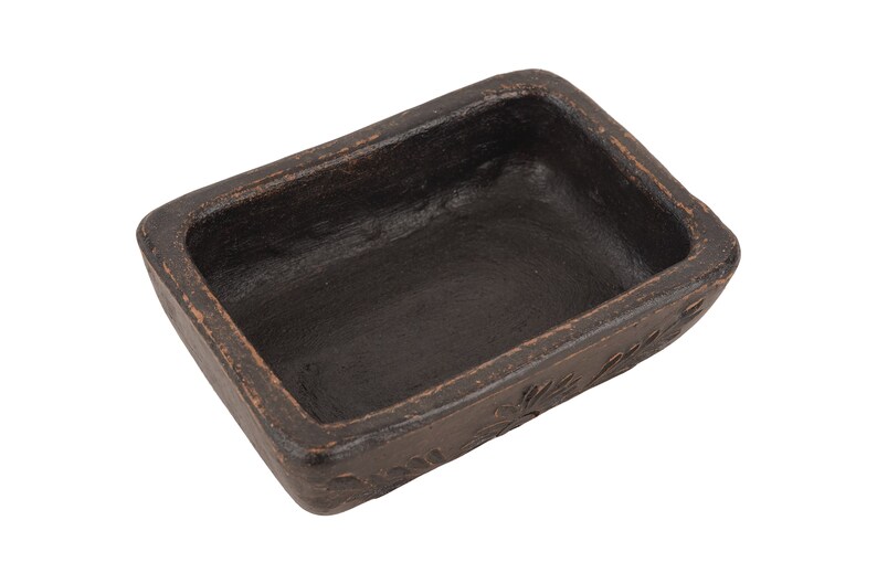 Pu&ograve; includere: Un piccolo piatto rettangolare in ceramica nera con un bordo leggermente rialzato. Il piatto ha una superficie testurizzata ed &egrave; vuoto.