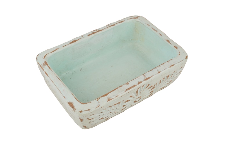 Pu&ograve; includere: Un vaso rettangolare in ceramica con una finitura bianca usurata e un interno blu chiaro. Il vaso ha un motivo floreale attorno al bordo.