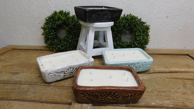 Pu&ograve; includere: Quattro candele rettangolari in contenitori decorativi. I contenitori sono bianchi, marroni, blu chiaro e neri. Le candele sono tutte bianche e hanno pi&ugrave; stoppini.