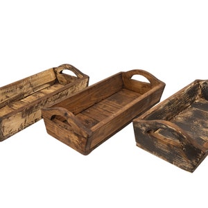May include: Three wooden trays with handles. The trays are made of natural wood with a rustic finish. The trays are different sizes and have a distressed look.