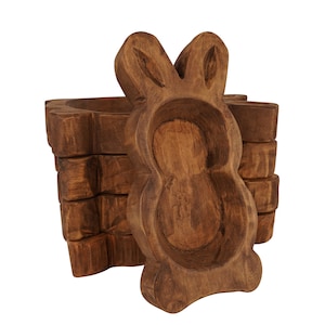 May include: A wooden rabbit-shaped bowl with a carved design. The bowl is made of dark brown wood and has a natural finish. The bowl is stacked on top of other wooden bowls.