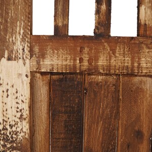 May include: Close-up of a wooden door with a weathered, brown finish. The door is made of vertical planks with a horizontal plank across the top. The wood has a natural grain pattern and shows signs of age and wear.