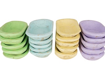 May include: A set of four stacks of small wooden bowls in pastel colors. The bowls are stacked in green, blue, yellow, and purple.