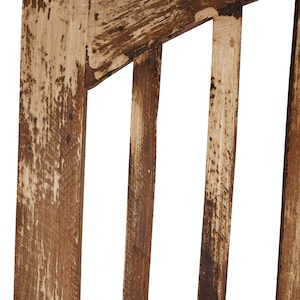May include: Close-up of a wooden chair back with a distressed brown finish. The chair back has vertical slats and a curved top.