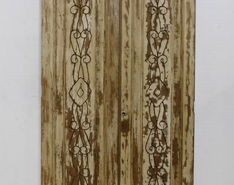 Puede incluir: Dos puertas antiguas de madera con un acabado blanquecino desgastado. Cada puerta presenta un diseño decorativo de filigrana metálica oscura en el centro. Las puertas tienen una parte superior arqueada y muestran signos de desgaste.