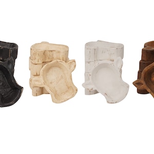 May include: Four wooden bowls shaped like cow heads. The bowls are stacked in groups of three. The bowls are painted in black, white, beige, and brown.