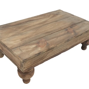 May include: A rustic wooden coffee table with a rectangular top and four turned legs. The table is made of natural wood with a light brown finish.