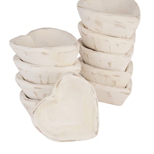 May include: A stack of white heart-shaped bowls with a distressed finish. The bowls are made of wood and are perfect for serving small snacks or dips.