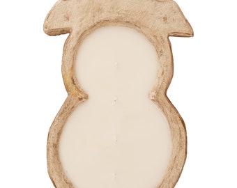 May include: A snowman-shaped candle with a creamy white wax fill. The candle is set in a distressed, light brown wooden holder. The holder has a rustic, weathered appearance, with a snowman outline and a hat.
