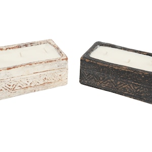 May include: Two rectangular candles in decorative containers. The containers are made of a textured material and have a white and black finish. The candles have three wicks each.