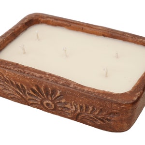 Pu&ograve; includere: Un portacandele rettangolare in ceramica marrone con una candela bianca all'interno. Il portacandele ha un design floreale.