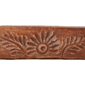 Pu&ograve; includere: Un vaso rettangolare in terracotta marrone con un motivo floreale scolpito. Il vaso ha un fondo leggermente arrotondato e una parte superiore piatta.