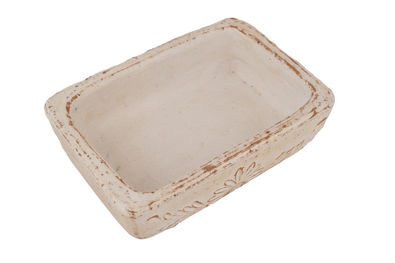 Pu&ograve; includere: Un piatto rettangolare in ceramica bianca con un design decorativo attorno al bordo. Il piatto ha un aspetto rustico e usurato.