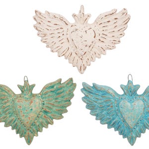 May include: Three heart-shaped wall hangings with wing details. One is white with brown accents, another is teal, and the third is light blue. Each has a distressed, rustic finish and a metal loop for hanging.
