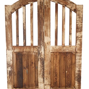 May include: A pair of weathered wooden doors with a decorative arched top and vertical slats. The doors are painted white with brown wood showing through.
