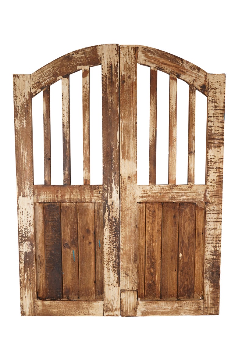 May include: A pair of weathered wooden doors with a decorative arched top and vertical slats. The doors are painted white with brown wood showing through.