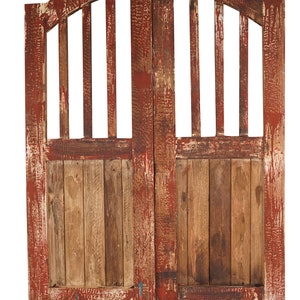 May include: A pair of weathered wooden doors with a red paint finish. The doors have a curved top and a slatted design. The wood is a natural brown colour with areas of red paint showing through.