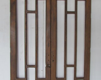Puede incluir: Un par de puertas antiguas de madera con un diseño de rejilla. Las puertas están hechas de madera marrón desgastada y presentan aberturas rectangulares y cuadradas, creando una apariencia de ventana. Las puertas están sobre un fondo blanco.
