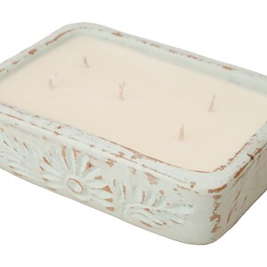 Pu&ograve; includere: Un portacandele rettangolare in ceramica blu chiaro con una candela bianca all'interno. Il portacandele ha una finitura usurata e un motivo floreale.