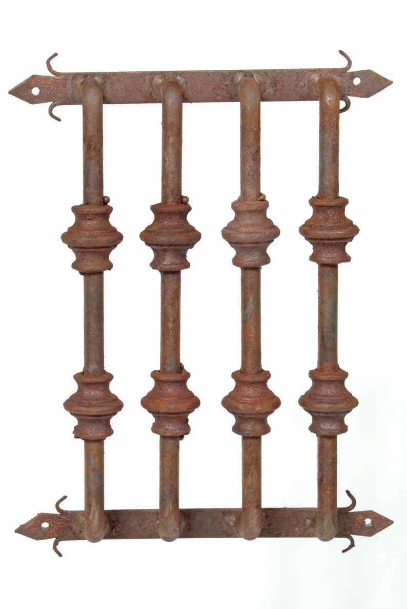 May include: A rusty metal window grate with four vertical bars and decorative finials. The grate is made of iron and has a rustic, aged appearance.