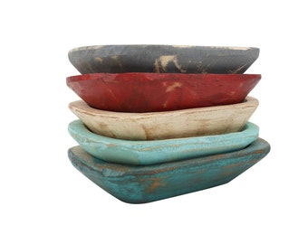 May include: A stack of five wooden dough bowls in various colors, including teal, white, red, and gray. The bowls are all slightly different sizes and shapes, and they have a rustic, distressed look.