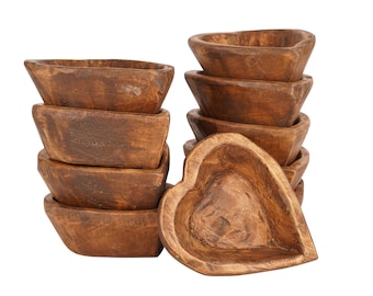 May include: A stack of brown wooden heart-shaped bowls, with one bowl lying on its side in front of the stack.