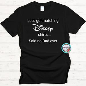 May include: Black t-shirt with white text that reads "Let's get matching Disney shirts... Said no Dad ever".