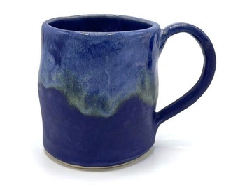 May include: A handmade ceramic mug with a blue and green glaze. The mug has a rounded body and a handle.