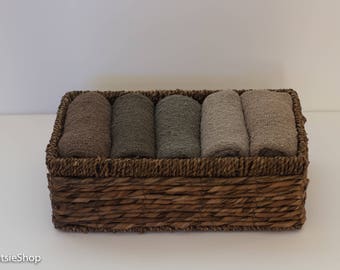 May include: A wicker basket filled with five rolled up towels in shades of brown and beige.
