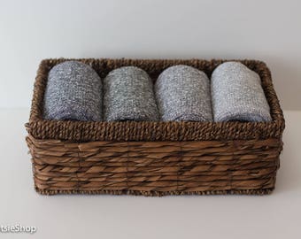 May include: A brown wicker basket filled with four gray and white striped fabric rolls.