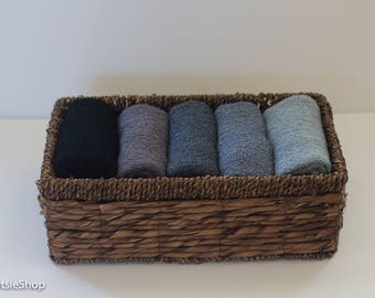 May include: A wicker basket filled with six rolled up fabric swatches in shades of gray and blue.