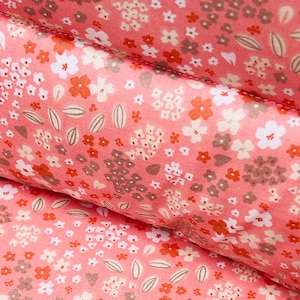 May include: Pink fabric with a floral pattern featuring small white, red, and brown flowers. The fabric has a subtle texture and a soft, delicate look.