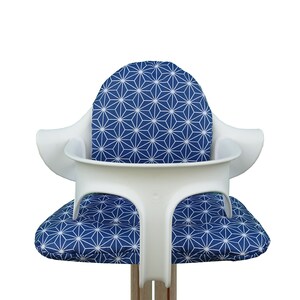 May include: White high chair with a blue and white geometric pattern cushion.