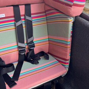 Ein rosa-grün gestreiftes Kissen für das Lovens Lastenrad. Das Polster für das Cargobike passt auch für Urban Arrow Family und Urban Arrow family next.    Es hat eine bequeme Kopfstütze für Kinder, die unterwegs einschlafen. So wird das Rad richtig gemütlich, sicher und bequem.