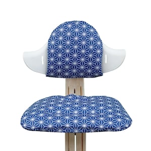 May include: A white chair with a blue and white geometric patterned cushion on the seat and back.