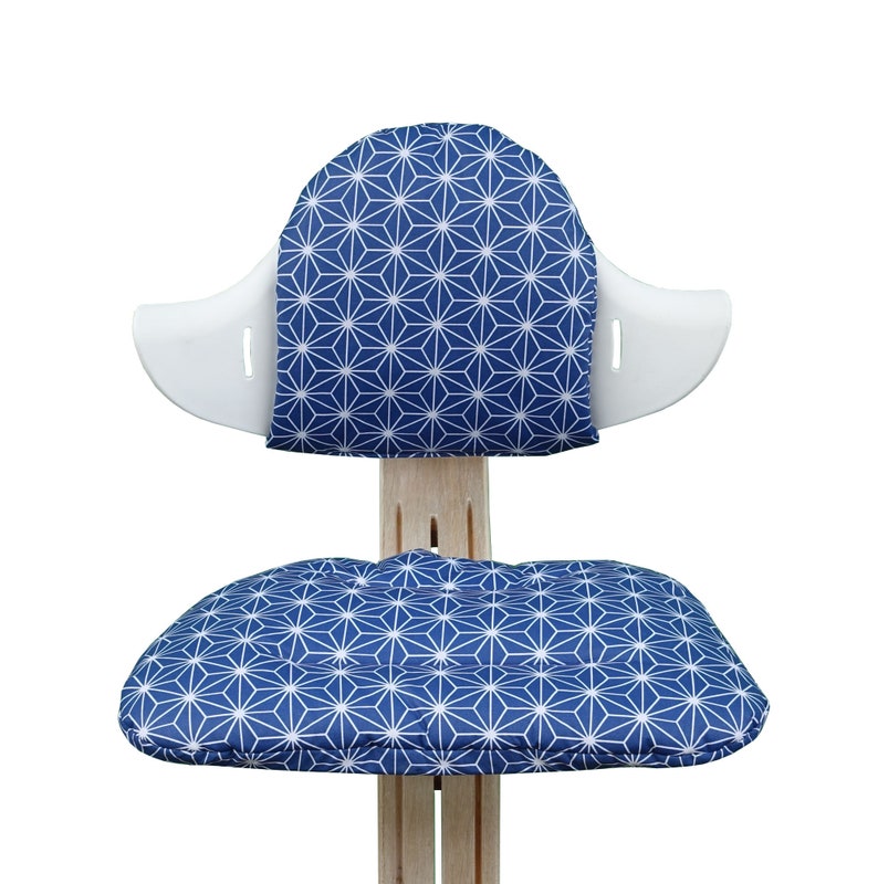 May include: A white chair with a blue and white geometric patterned cushion on the seat and back.