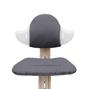 May include: A gray and white chair with a padded seat and back. The chair has a white, curved back with a gray, polka-dot patterned cushion. The seat is also gray with a polka-dot pattern.