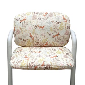 Op de afbeelding: Witte stoel met een zitting en rugleuning met een herhaald patroon van oranje vossen, bomen en bladeren in beige, bruin en geel. Het frame van de stoel is wit.
