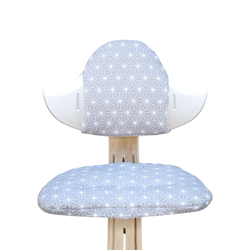 May include: A white and gray ergonomic chair with a geometric patterned cushion. The chair has a unique design with a curved backrest and a rounded seat.