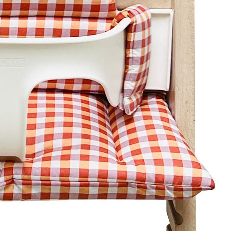 May include: A red and white checkered high chair cushion with a white plastic tray attached.