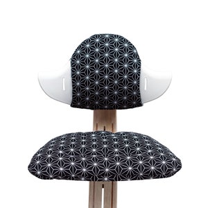 May include: A black and white geometric patterned chair with a white back and a separate cushion. The chair is made of wood and has a modern design.