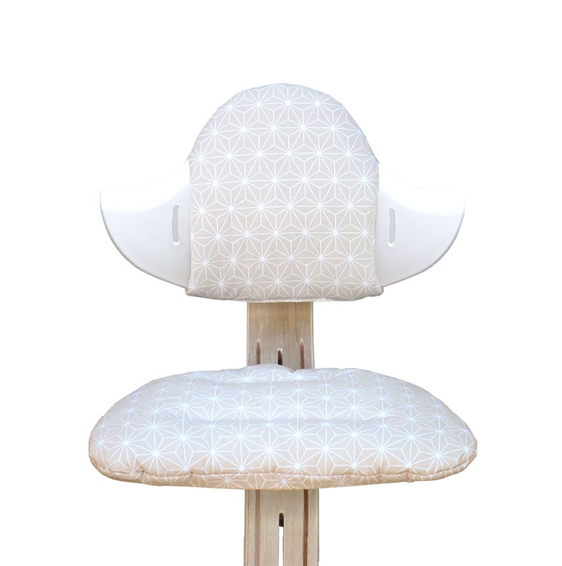 May include: A white wooden chair with a beige cushion and back rest. The cushion and back rest have a geometric pattern of white stars on a beige background.