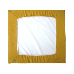 May include: A mustard yellow fitted sheet with a white border. The sheet is made of a soft, textured fabric.