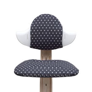 May include: A white and gray children's chair with a star pattern on the seat and back. The chair has a unique design with a curved back and a wide seat.