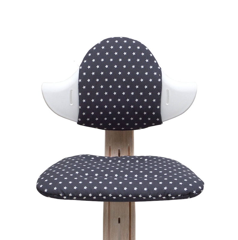 May include: A white and gray children's chair with a star pattern on the seat and back. The chair has a unique design with a curved back and a wide seat.