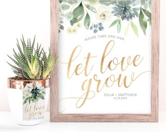 May include: A framed wedding sign with a watercolor floral design and gold lettering that says "Please take one and let love grow." The sign also includes the couple's names and wedding date: Julia + Matthew 11.24.2018.