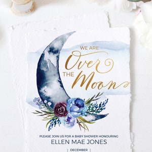 Peut inclure: Une invitation &agrave; une f&ecirc;te pr&eacute;natale avec une illustration aquarelle d'un croissant de lune orn&eacute; de motifs floraux. Le texte indique "We are Over the Moon" en lettres dor&eacute;es. L'invitation comprend la date, l'heure, le lieu et les informations RSVP pour la f&ecirc;te pr&eacute;natale d'Ellen Mae Jones.