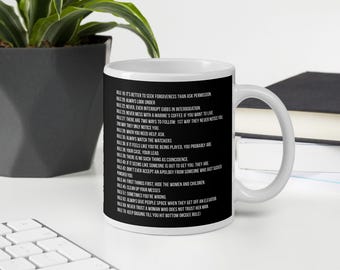 Könnte beinhalten: Eine weiße Keramiktasse mit schwarzem Henkel und einem schwarzen Design auf der Vorderseite. Das Design ist eine Liste von Regeln, darunter "Es ist besser, um Vergebung zu bitten, als um Erlaubnis zu fragen" und "Schau immer unter".