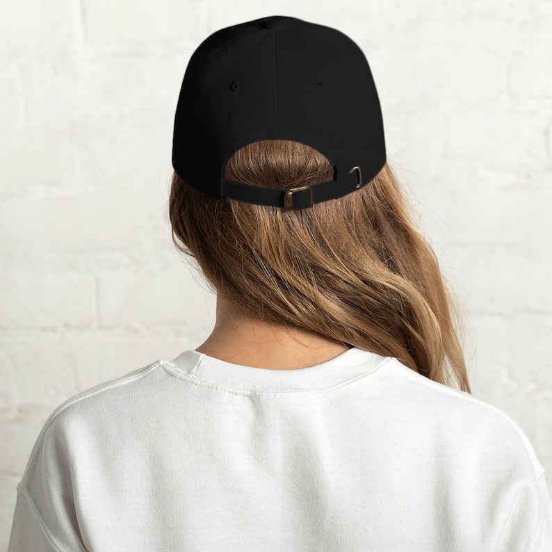 K&ouml;nnte beinhalten: Eine einfarbige schwarze Baseballkappe mit sechs Paneelen und einem gebogenen Schirm. Auf der R&uuml;ckseite befindet sich ein verstellbarer Stoffriemen mit einer Metallschnalle, der eine individuelle Anpassung an verschiedene Kopfgr&ouml;&szlig;en erm&ouml;glicht.